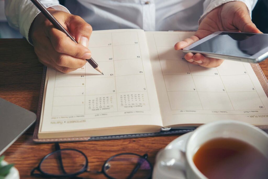 person writing on calendar