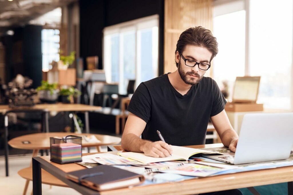 freelance man taking notes at his computer