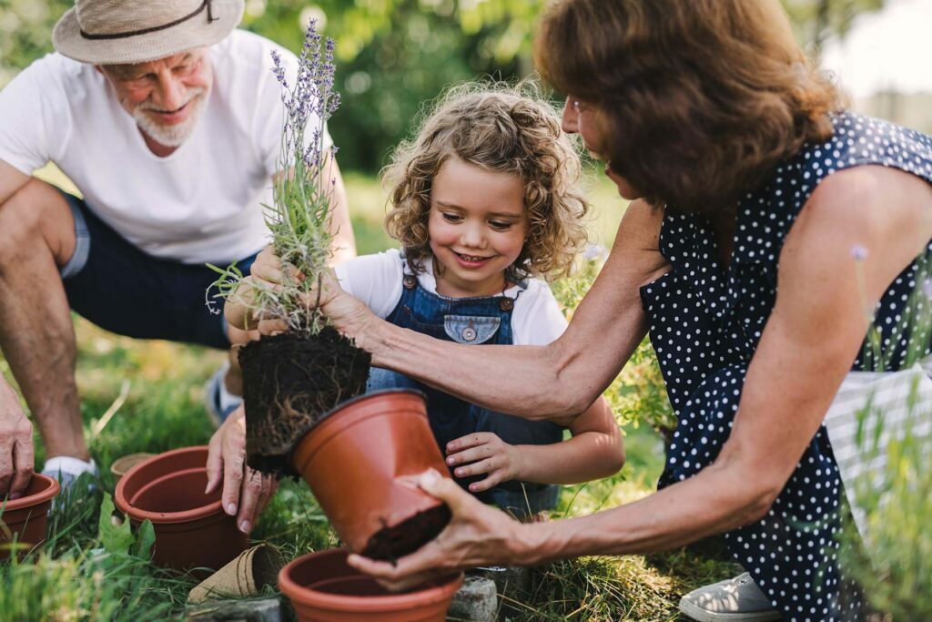 family planting potted plants outside in summer