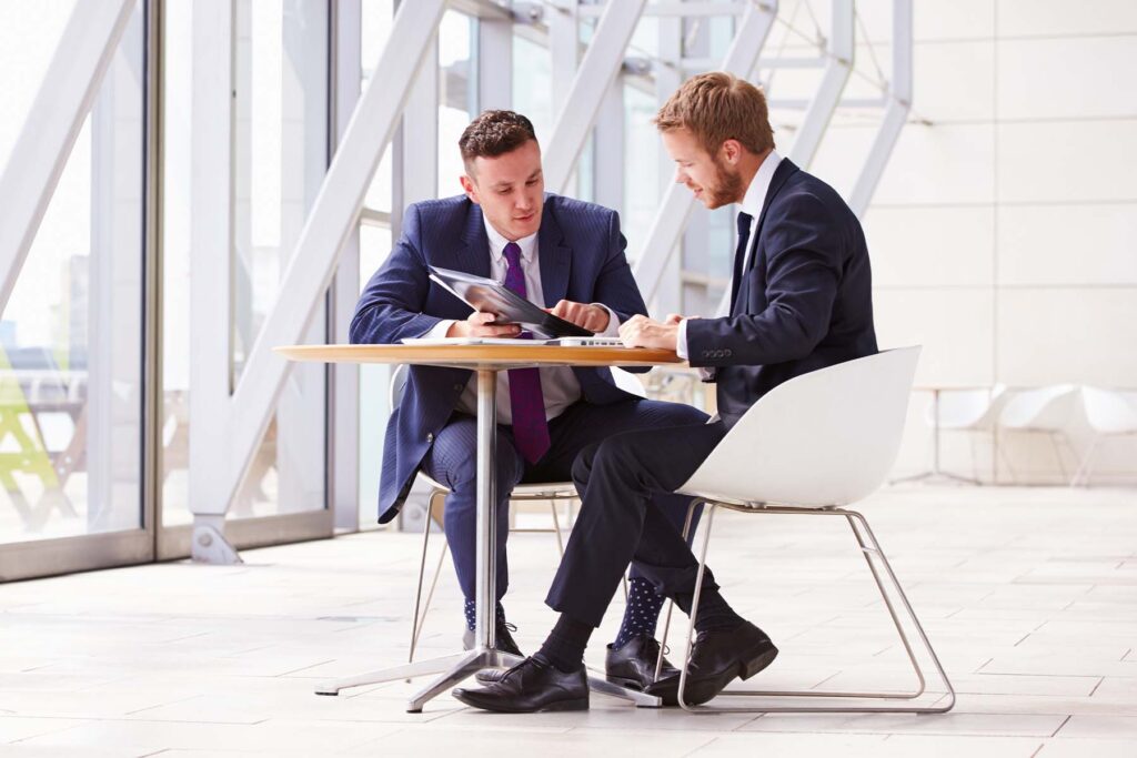 two business men at table talking about a loan