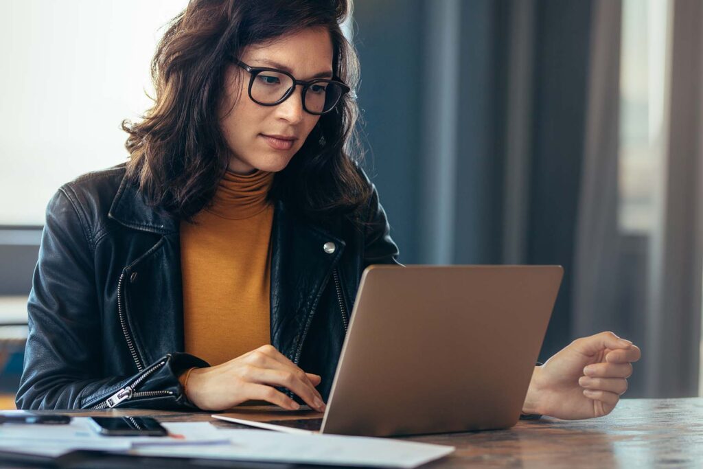 lady in leather jacket at her laptop looking at online reviews