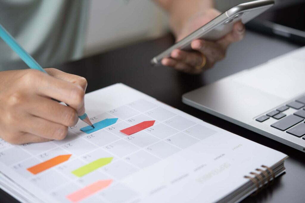 person writing deadlines on calendar