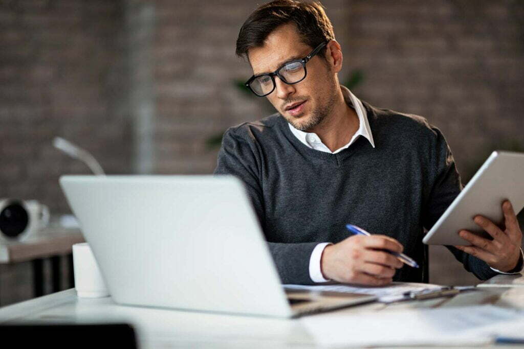 man going over payroll documents on his computer