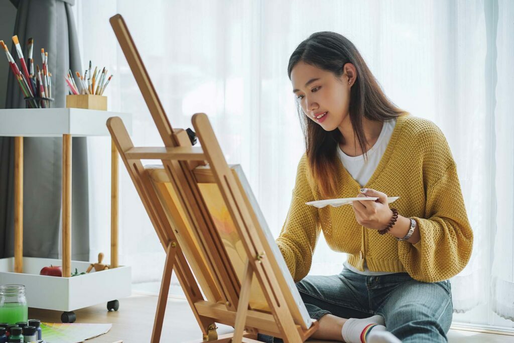 A happy lady painting using self-care tips