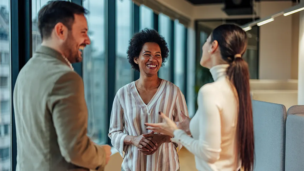 3 employees talking near window
