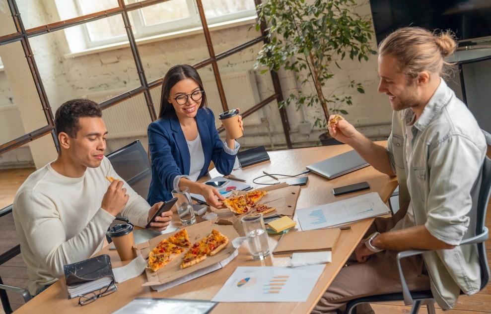 group of employees eating pizza at table